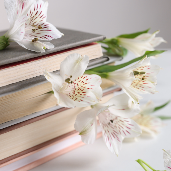 stack of books with flowers on top and coming out from between pages